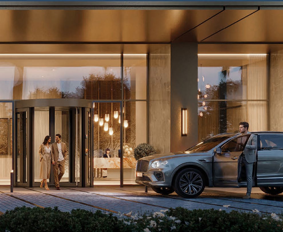 Couple leaving the glowing entrance as a car waits at the drop-off